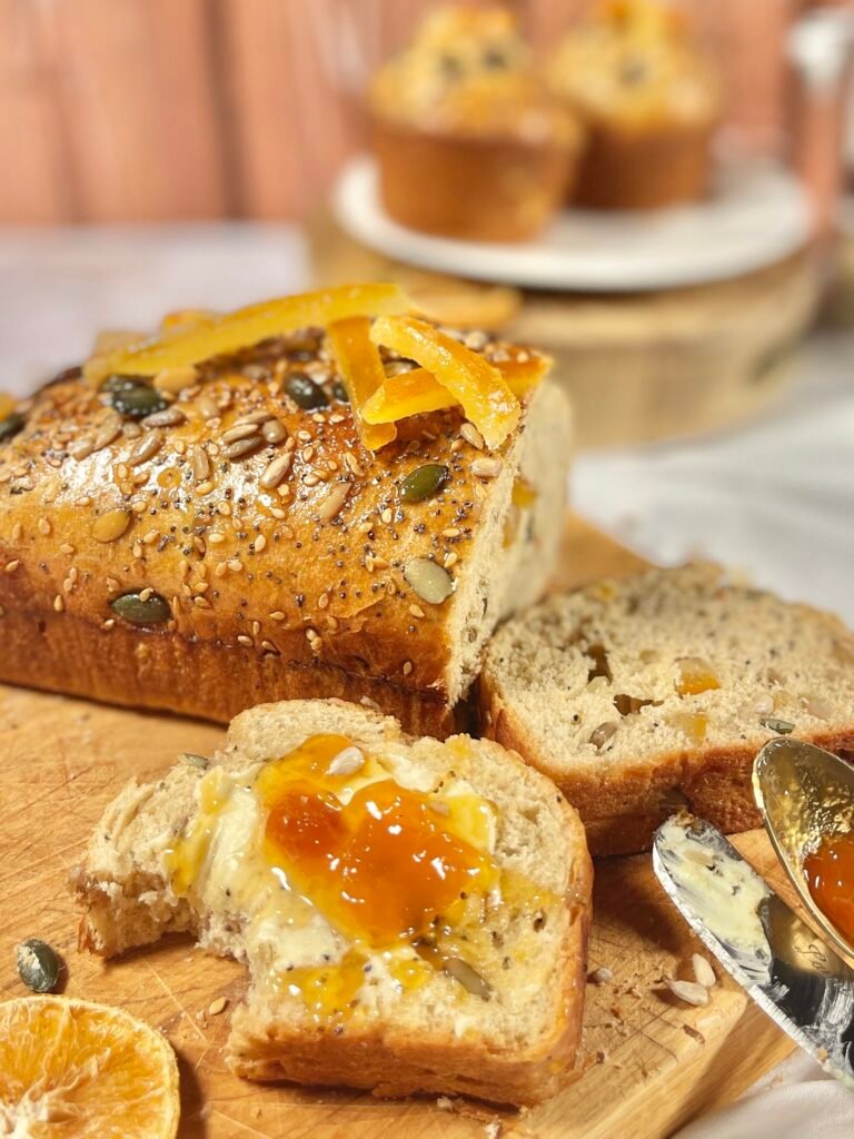 Une tranche de brioche maison tartinée de beurre et de confiture, mettant en valeur la texture filante et la douceur des agrumes confits.