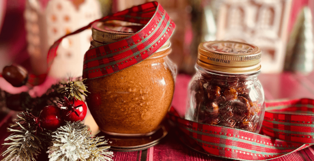 Pâte de praliné maison aux amandes et noisettes, lisse et gourmande, présentée dans un bocal enrubanné, mise en valeur avec des décorations de Noël. Recette festive et généreuse à retrouver sur Deliciously Home