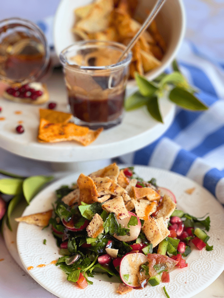 Salade printanière façon fattouche, avec radis, persil, grenade, et pain pita croustillant sur assiette blanche – recette fraîche sur DeliciouslyHome.com.
