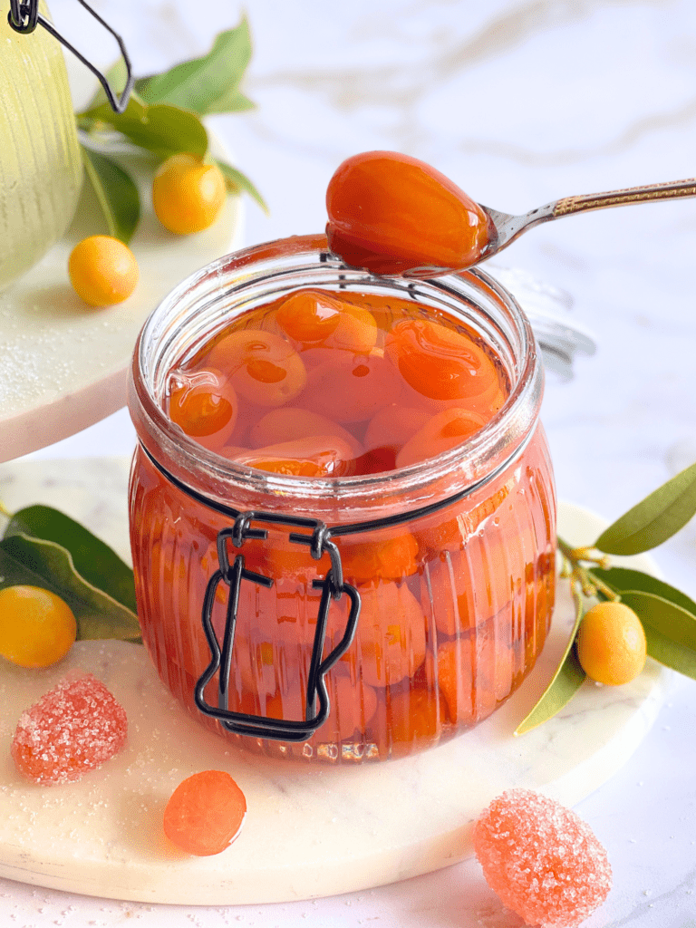 Deux trésors de conservation : fruits confits et sirop de kumquats maison capturant la lumière sur deliciouslyhome.com.