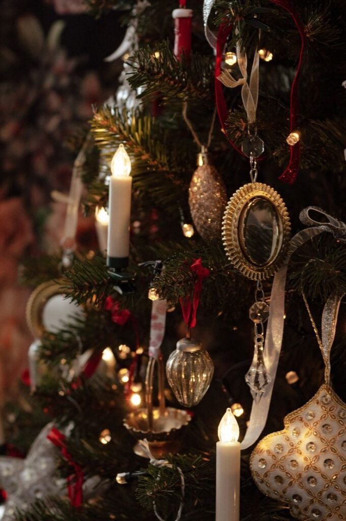 Grand sapin de Noël illuminé de guirlandes dorées dans un salon classique, avec jouet ancien rouge à ses pieds — une scène digne d’un décor Ralph Lauren.