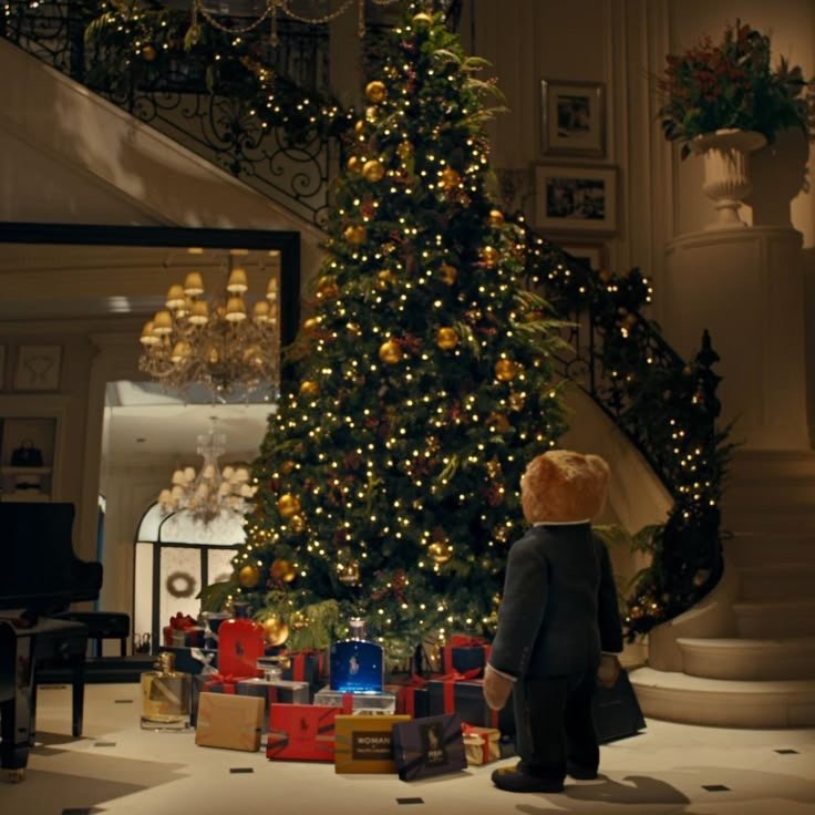 Grand sapin de Noël décoré de guirlandes lumineuses dorées, entouré de cadeaux et d’un ourson Polo Bear vêtu d’un costume, dans un intérieur élégant de style Ralph Lauren.