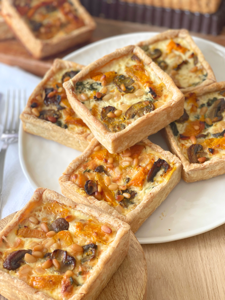 Vue légèrement plongeante sur un assemblage de quiches carrées, dorées à souhait. On y retrouve toute la générosité d’une recette née d’un souvenir parisien et réinterprétée à la maison, Deliciously Home.