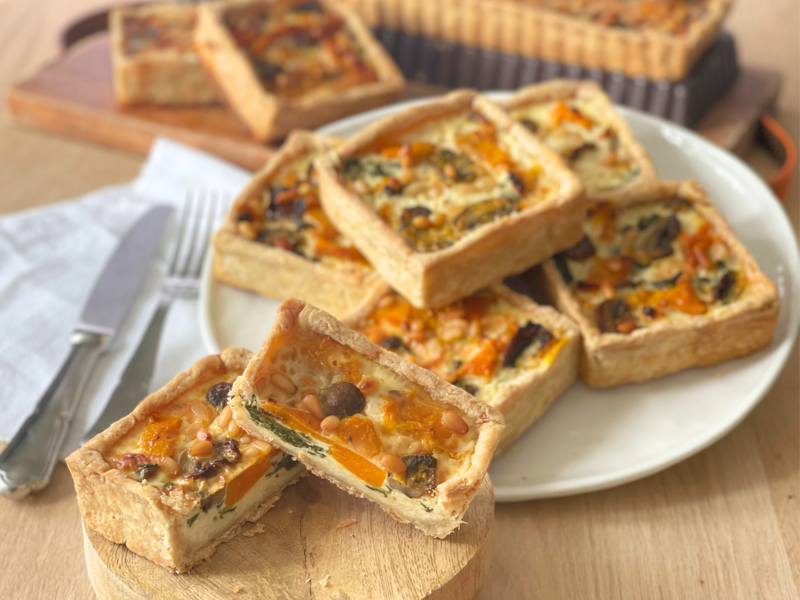 Un gros plan sur la découpe nette d’une quiche individuelle, où l’on distingue les couches : pâte croustillante, appareil crémeux, légumes rôtis. Une quiche d’automne comme on aime les faire chez Deliciously Home.
