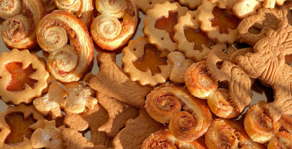 Plateau de biscuits de Noël sucrés issus des trois recettes proposées dans l’article « Biscuits de Noël sucrés, 3 recettes à préparer et à offrir » sur Deliciously Home. Spéculoos, palmiers pécan-cannelle et biscuits vitrail sont réunis comme une boîte à partager, dans l’esprit d’un Noël fait maison et offert avec soin.