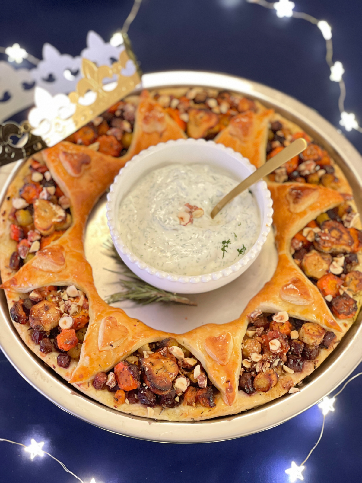 Galette des rois salée végétarienne aux légumes rôtis et topping de noisettes, présentée en couronne ouverte. Article et recette sur Deliciously Home.