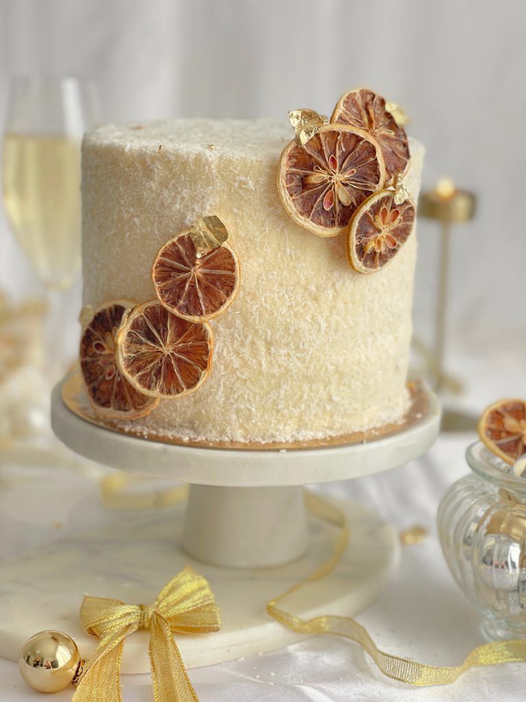 Layer cake coco-citron décoré de rondelles de citron séché et feuille d’or, une recette signée Deliciously Home pour les fêtes de fin d’année.
