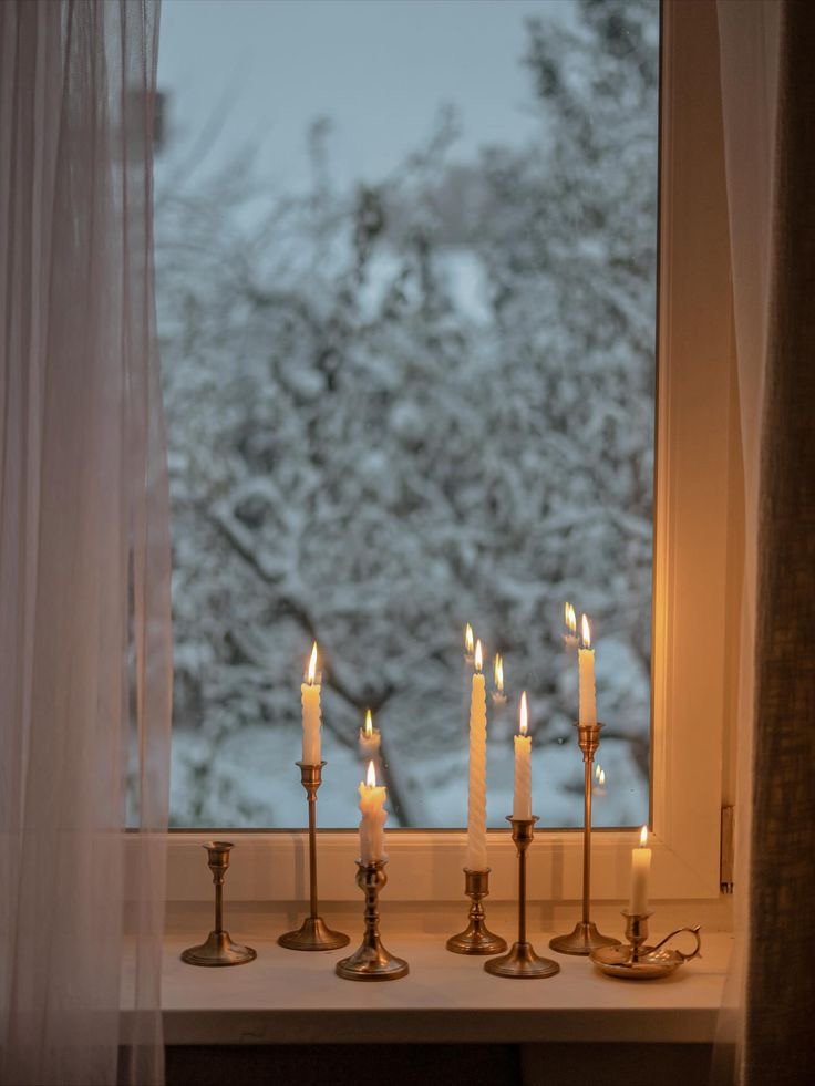 soft minimalism white winter deliciouslyhome 1 Bougies blanches sur un rebord de fenêtre face à un paysage enneigé, lumière douce et apaisante. Inspiration soft minimalism d’hiver, à découvrir sur le blog Deliciously Home