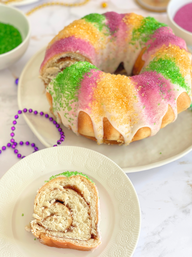 Tranche de brioche de Mardi Gras King Cake révélant une pâte levée soyeuse et une garniture à la cannelle, brioche festive traditionnelle. Une recette Deliciously Home.