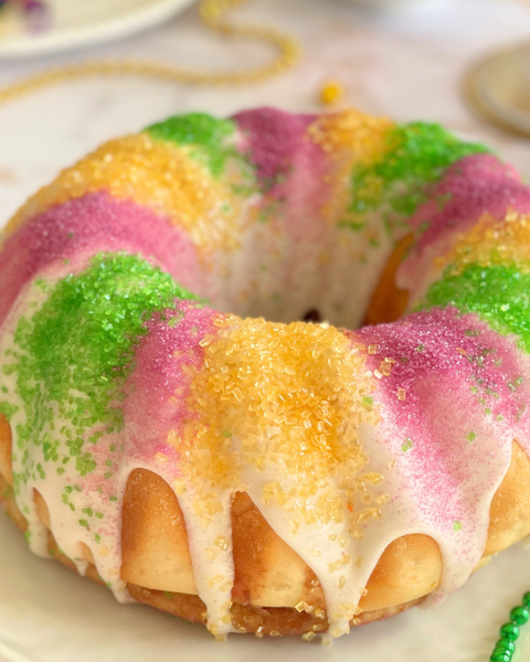 Mardi Gras King Cake en couronne, brioche dorée et glaçage coloré violet, vert et or, spécialité du carnaval louisianais. Une recette Deliciously Home.