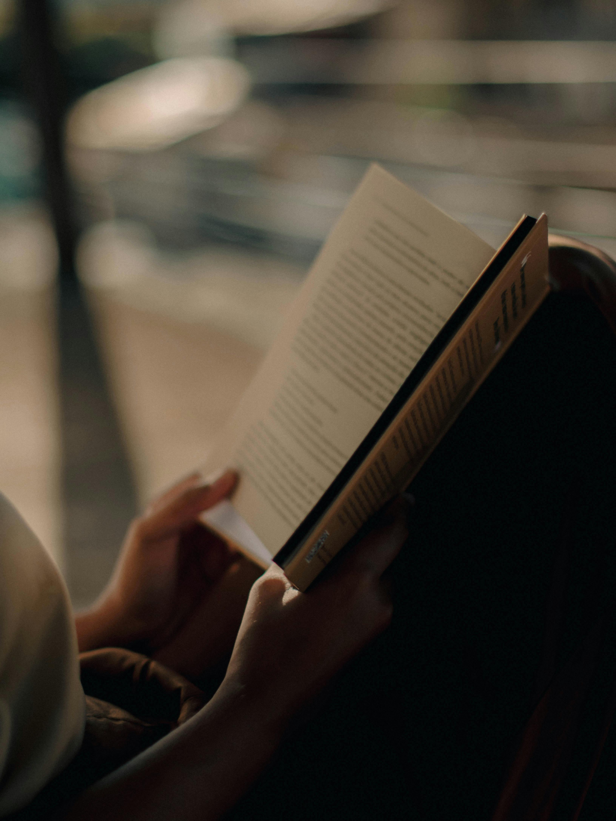 Personne lisant un roman dans une ambiance douce, lumière tamisée et moment de lecture calme. Découvrez nos idées lecture sur Deliciously Home.