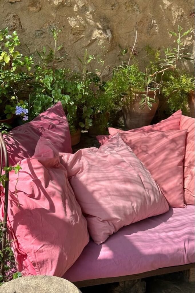 Canapé extérieur avec coussins roses dans un jardin
