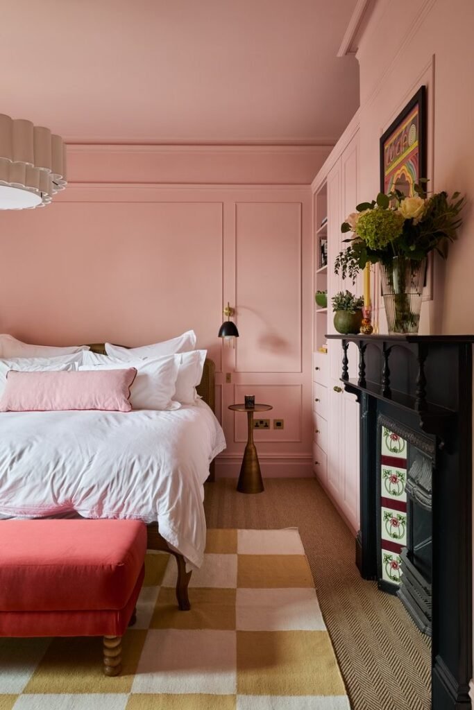 Chambre rose avec lit blanc et cheminée