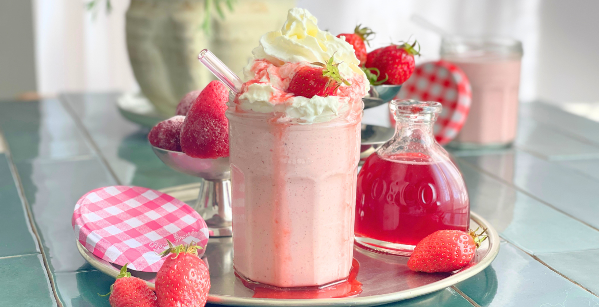 homepage milkshake fraise boisson glacee deliciouslyhome Milkshake fraise vanille servi dans un pot en verre avec chantilly, fraise fraîche et sirop de fraise, ambiance rétro