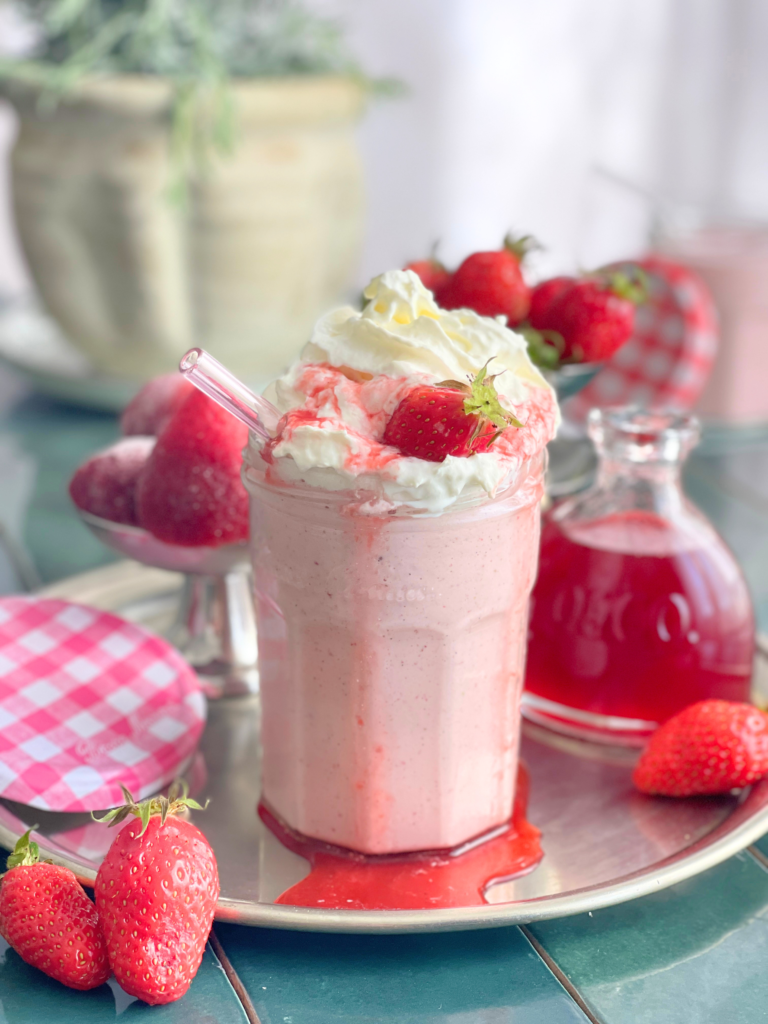 Milkshake fraise avec chantilly et fraise fraîche, texture épaisse et crémeuse, servi dans un pot type confiture