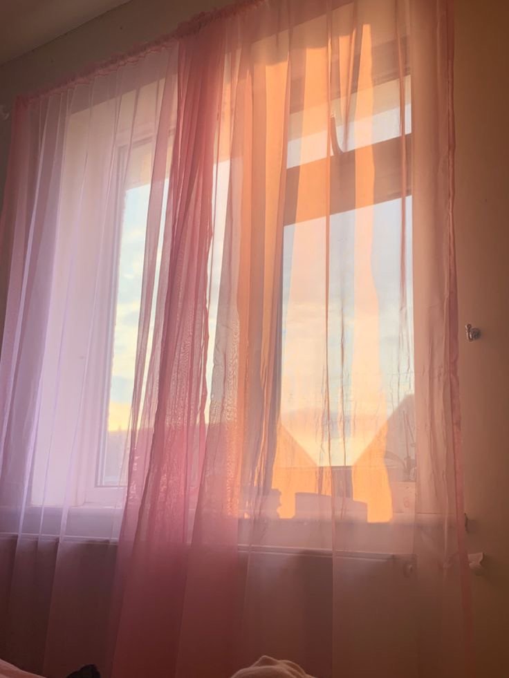 Rideaux roses devant une fenêtre au coucher du soleil