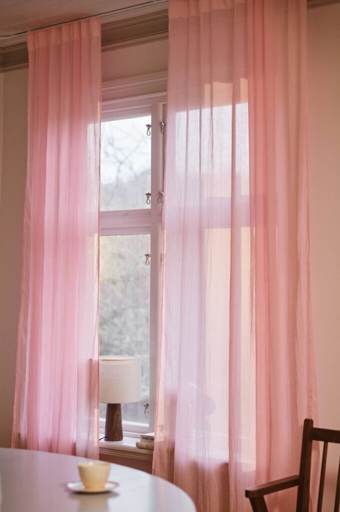 Rideaux roses filtrant la lumière à une fenêtre