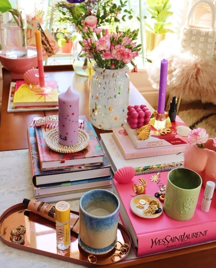 Table colorée avec livres, bougies et objets déco rose