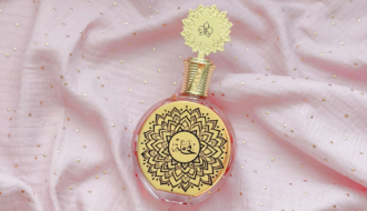 Parfum Fakhama de Maison Asrar sur tissu rose lumineux, signature olfactive de mars sur Deliciously Home, gourmand floral inspiré de Love Don’t Be Shy