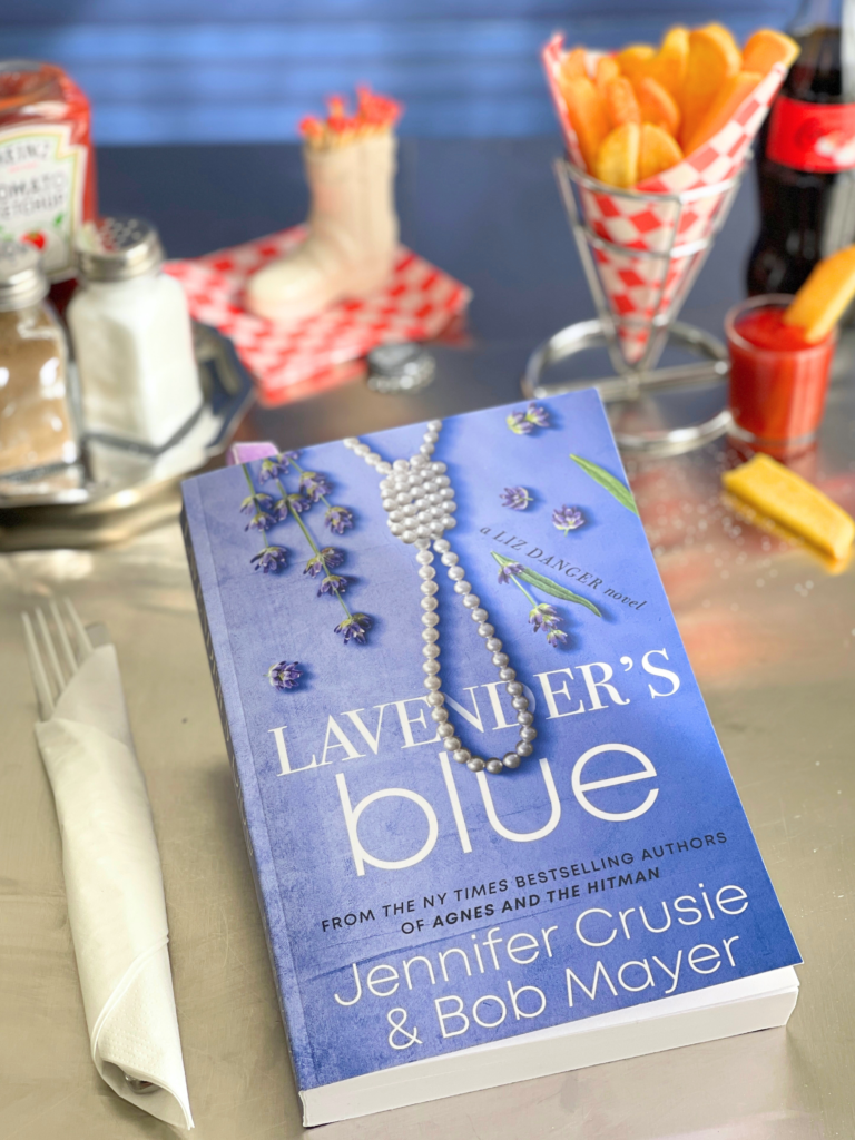 Lavender’s Blue de Jennifer Crusie et Bob Mayer posé sur une table de diner rétro, illustration d’une rom-com small town pour la lecture d’avril Deliciously Home.