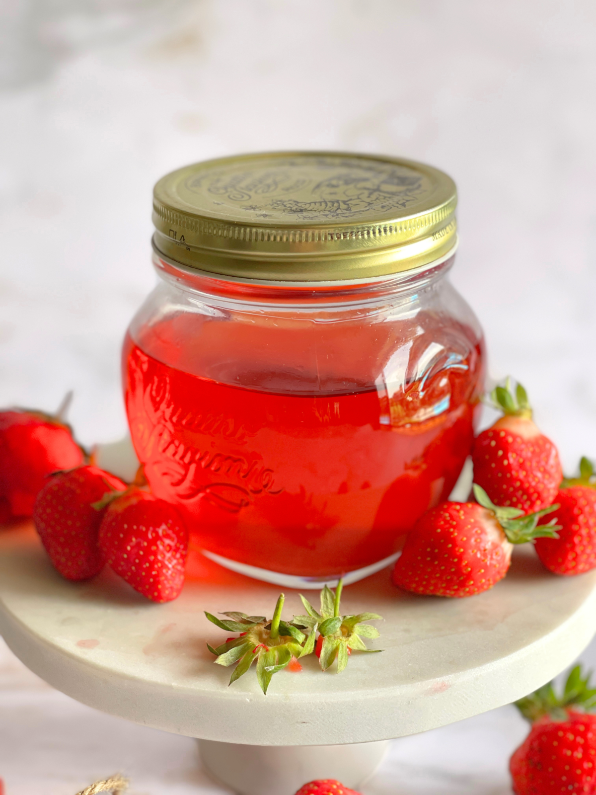 Détail d’un vinaigre de parures de fraises en cours de préparation, montrant les parties supérieures des fraises utilisées pour une recette de vinaigre maison naturelle et durable sur notre blog Deliciously Home.