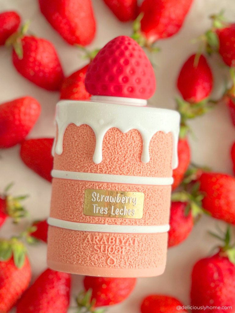 Strawberry Tres Leches d’Arabiyat Sugar, notre signature olfactive du mois d'avril, posé au milieu de fraises fraîches, une mise en scène qui reflète la note principale du parfum, détaillée dans notre avis DeliciouslyHome avec une description précise de ses notes olfactives fruitées et lactées.