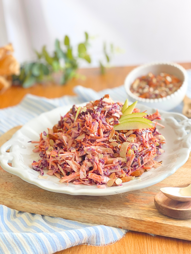 Coleslaw maison au chou rouge, carottes, pommes et amandes grillées pour une salade croquante et fraîche. Recette complète sur Deliciously Home.