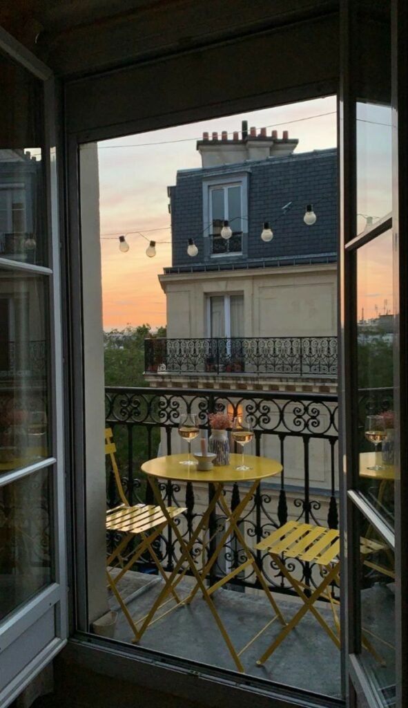 Balcon avec table bistrot, chaises pliantes et verres pour un apéritif au coucher du soleil, à voir dans notre article sur Aménager un coin d’été chez soi sur Deliciously Home