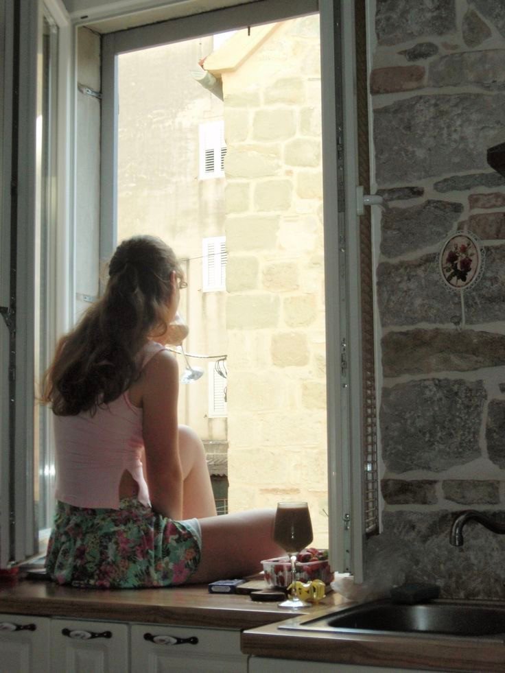 Coin fenêtre intérieur avec assise, lumière naturelle et vue sur jardin verdoyant en été, à explorer dans notre article sur Aménager un coin d’été chez soi sur Deliciously Home