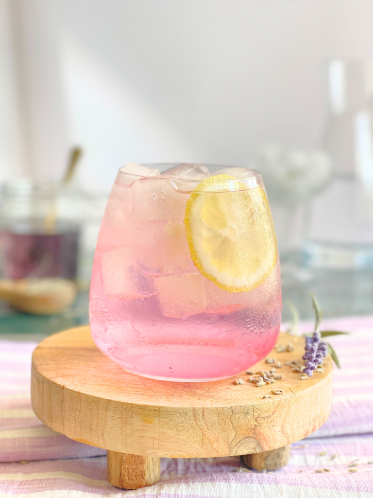 Cocktail gin tonic à la lavande servi sur glace avec une tranche de citron frais. Une recette florale et rafraîchissante imaginée par Deliciously Home pour les apéritifs d’été.