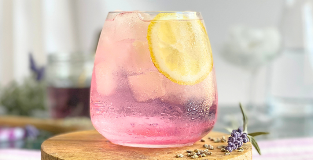 Cocktail gin tonic lavande floral servi sur glace avec une tranche de citron. Une recette estivale et botanique imaginée par Deliciously Home.