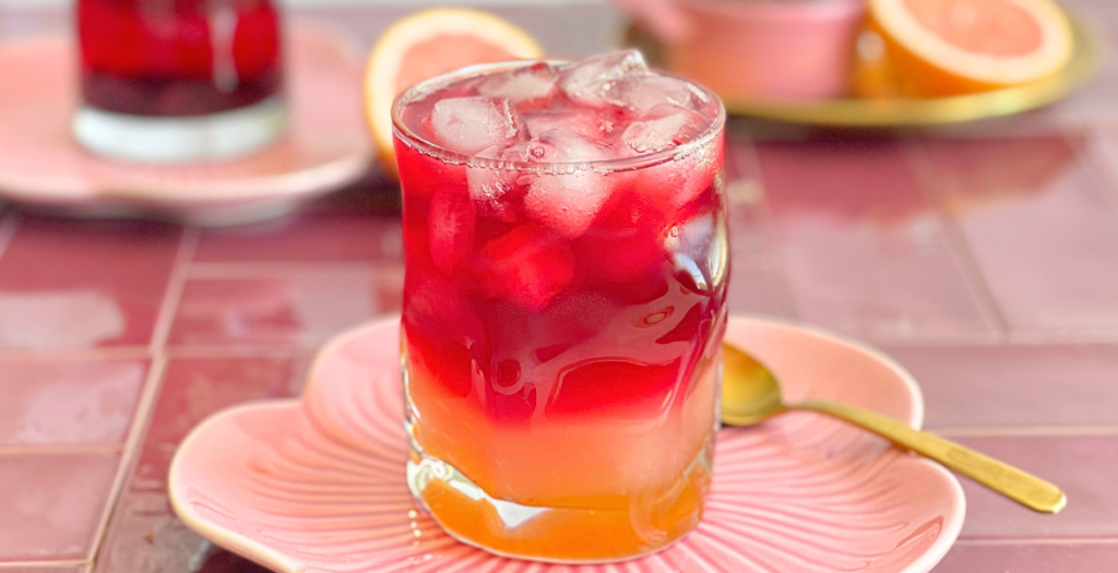 Mocktail glacé au pamplemousse rose et hibiscus aux couleurs vibrantes. Découvrez la recette sur Deliciously Home.