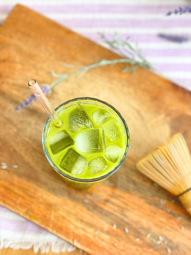Vue du dessus d’un matcha latte glacé à la lavande avec glaçons et fouet en bambou. Une recette estivale et florale créée par Deliciously Home.
