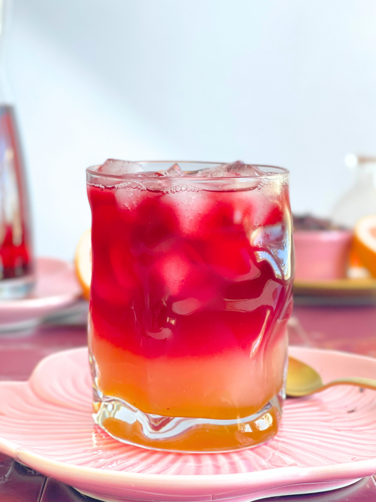 Mocktail rose au pamplemousse et hibiscus avec effet dégradé fruité. Découvrez la recette sur Deliciously Home.