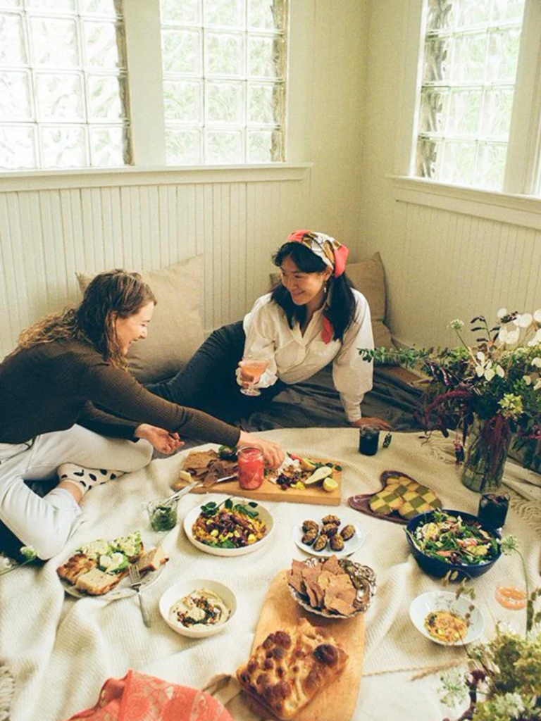 Créer une ambiance pique-nique chez soi peut commencer par une simple nappe au sol, quelques coussins et un repas partagé entre amis, pour transformer un coin de salon en parenthèse estivale. À découvrir avec Deliciously Home