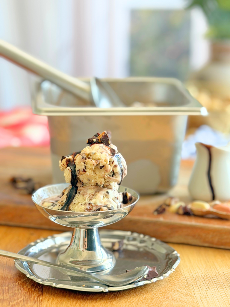 Coupe de glace Tin Roof maison garnie de sauce fudge et d'éclats de cacahuètes enrobées de chocolat. Recette à découvrir sur Deliciously Home.