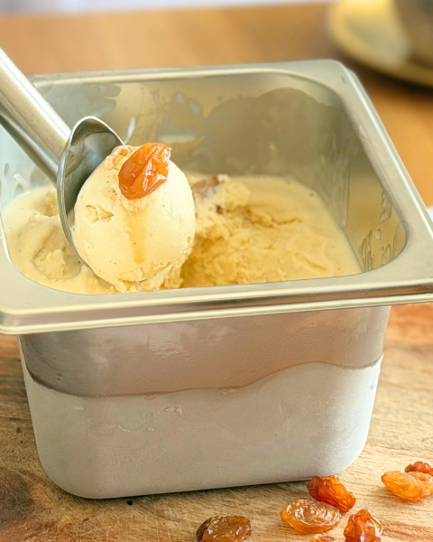Glace rhum-raisin maison servie dans un bac à glace avec des raisins macérés et un verre de rhum. Recette à découvrir sur Deliciously Home.