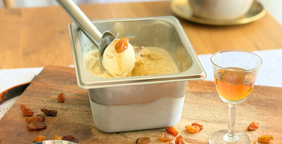 Glace rhum-raisin maison servie dans un bac à glace avec des raisins macérés et un verre de rhum. Recette à découvrir sur Deliciously Home.