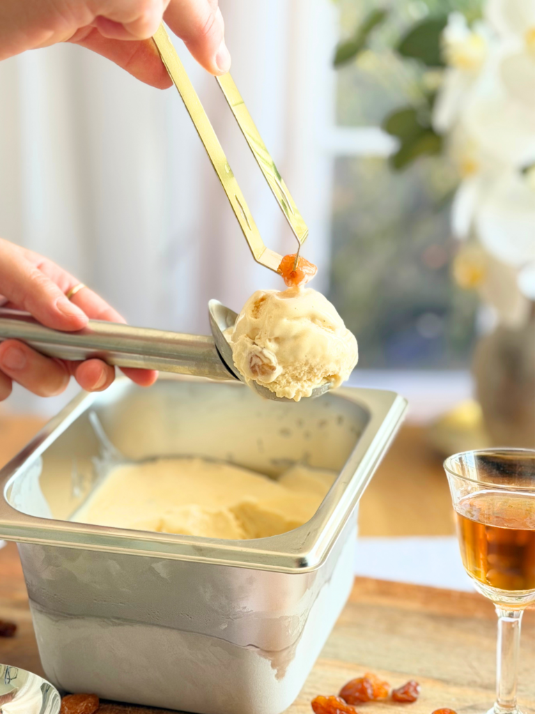 Boule de glace rhum-raisin maison garnie d'un raisin macéré, servie directement à la cuillère. Recette à découvrir sur Deliciously Home.