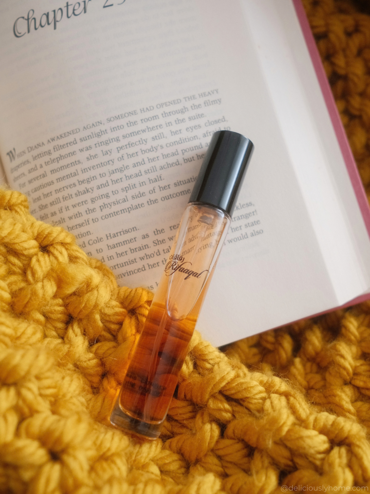 Rifaaqat de Paris Corner, parfum d’automne chaud et boisé, posé sur un livre et une maille épaisse pour évoquer le retour au confort de la maison sur Deliciously Home.
