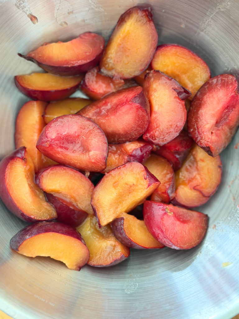 Prunes rouges coupées en quartiers dans un récipient, étape de préparation du chutney maison Deliciously Home.