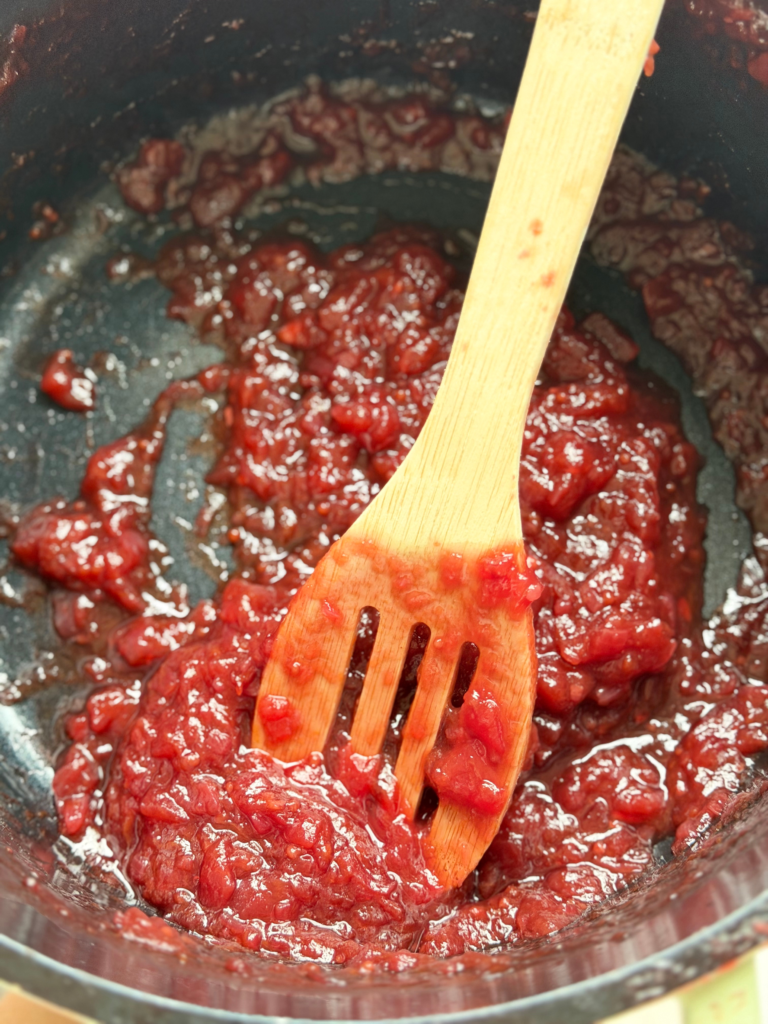 Chutney de prunes réduit et épaissi dans une casserole, mélangé à la spatule en bois, recette Deliciously Home.