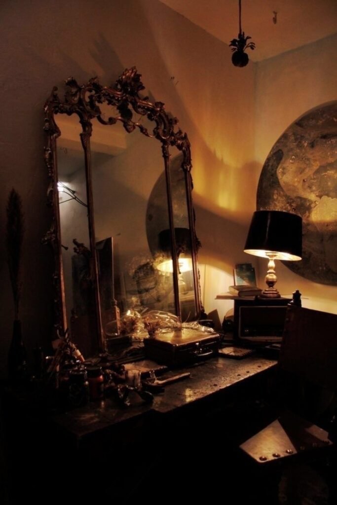 Coiffeuse en bois sombre avec grand miroir ancien et lampe à abat-jour noir créant une atmosphère nocturne et mystérieuse, parmi nos inspirations whimsigoth sur Deliciously Home.