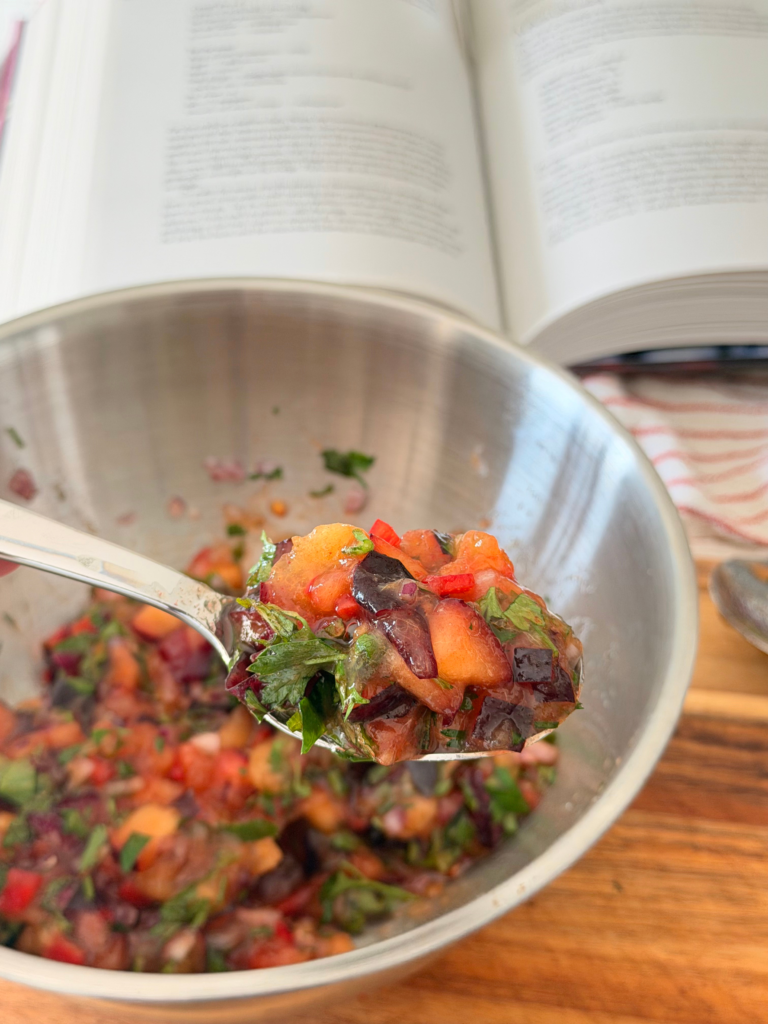 Mélange coloré de prunes violettes, herbes fraîches, oignon rouge et piment préparé pour le taboulé aux prunes. Retrouvez la recette sur Deliciously Home.